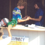 woman  praying at fair booth while little boy swipes toy
